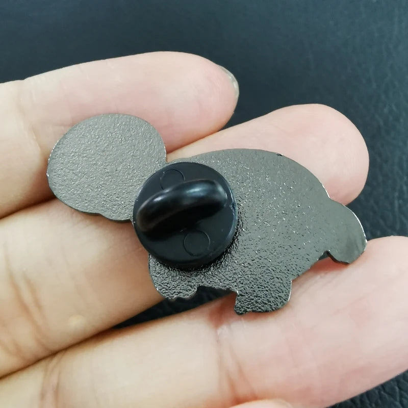 Metallic elephant-shaped object with a black center held in a hand against a dark background